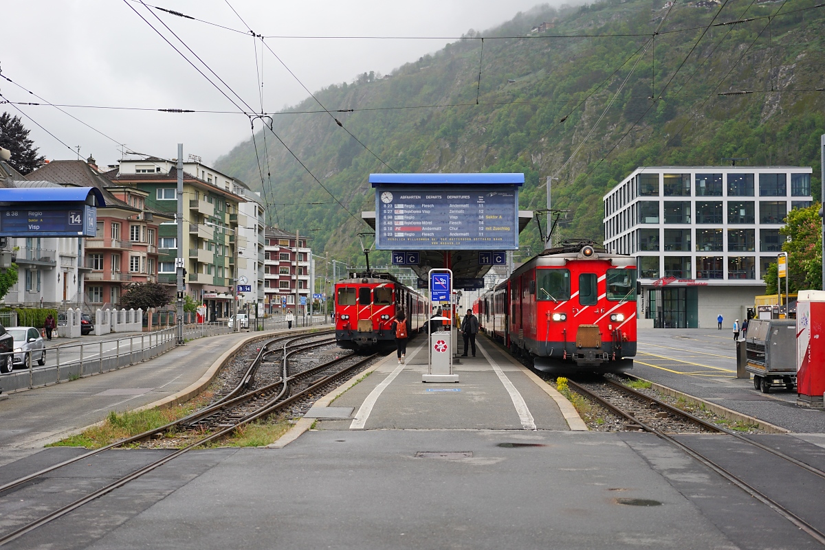 Am 07.05.2025 treffen sich Deh I 54 vor einem Regio nach Andermatt und Deh II 95 am Schluss eines RE nach Zermatt auf dem Bahnhofsvorplatz in Brig 
