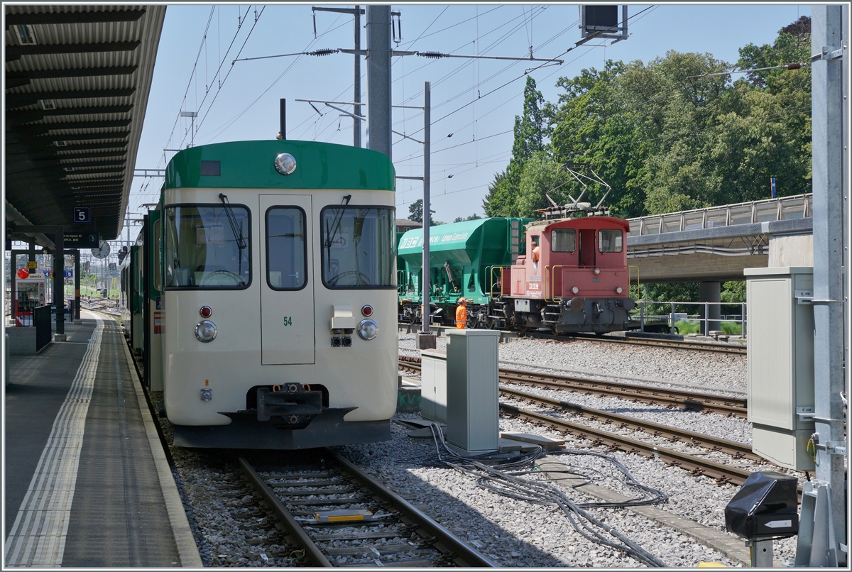 Der BAM MBC Te III 147 schiebt in Morges die normalspurigen Kieswagen auf die Rollbockanlage, während links im Bild eine BAM MBC Regionalzug auf die Abfahrt nach Bière wartet. 

19. Juli 2021