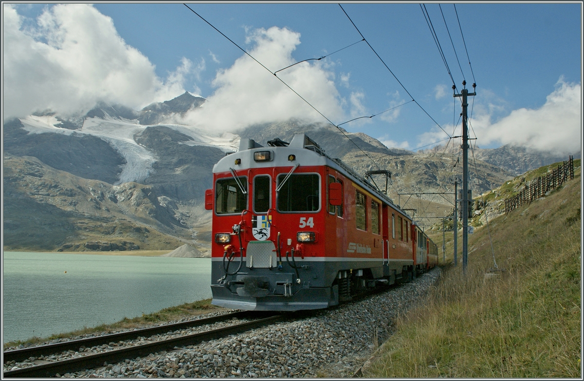 Im Schatten einer Wolke fahrt der Bernina ABe 4/4 N� 53 mit einem Schwestertriewagen  und einem langen Regionalzug nach Tirano am Lac Bianco entlang und erreicht in K�rze Ospizio Bernina. 
10. Sept. 2011