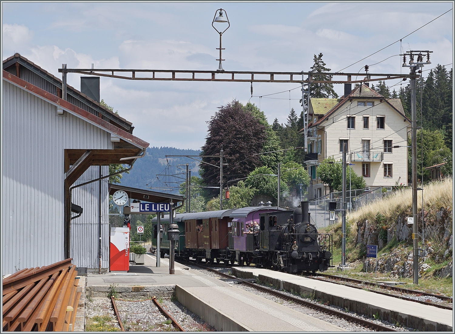 Das CTVJ (Compagnie du Train à Vapeur de la Vallée de Joux) Tigerli E 3/3 8494 (UIC 90 85 0008 494-6) der SLM mit Baujahr 1909 erreicht mit seinem Dampfzug Le Lieu, wo die Kreuzung mit dem entgegenkommenden Flirt nach Aigle abgewartet werden muss. 

23. Juli 2023