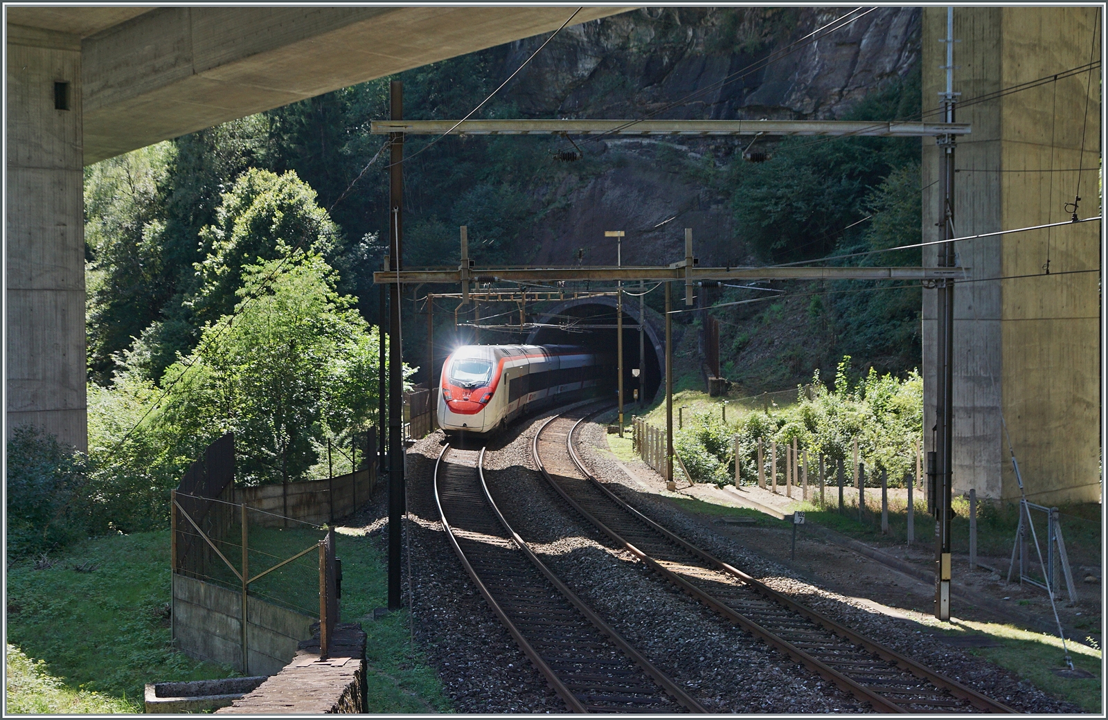 Die Gotthard Panorama Strecke bietet nicht nur herrliche Panorma-Bilder sondern an wenigen Stellen eher Tristesse: In der vom Beton der Autobahn A 2 verschandelten Landschaft fährt ein (umgeleiteter) SBB RABE 501  Giruno  auf dem Weg in Richtung Lugano in den Polmengokehrtunnel. 

4. September 2023