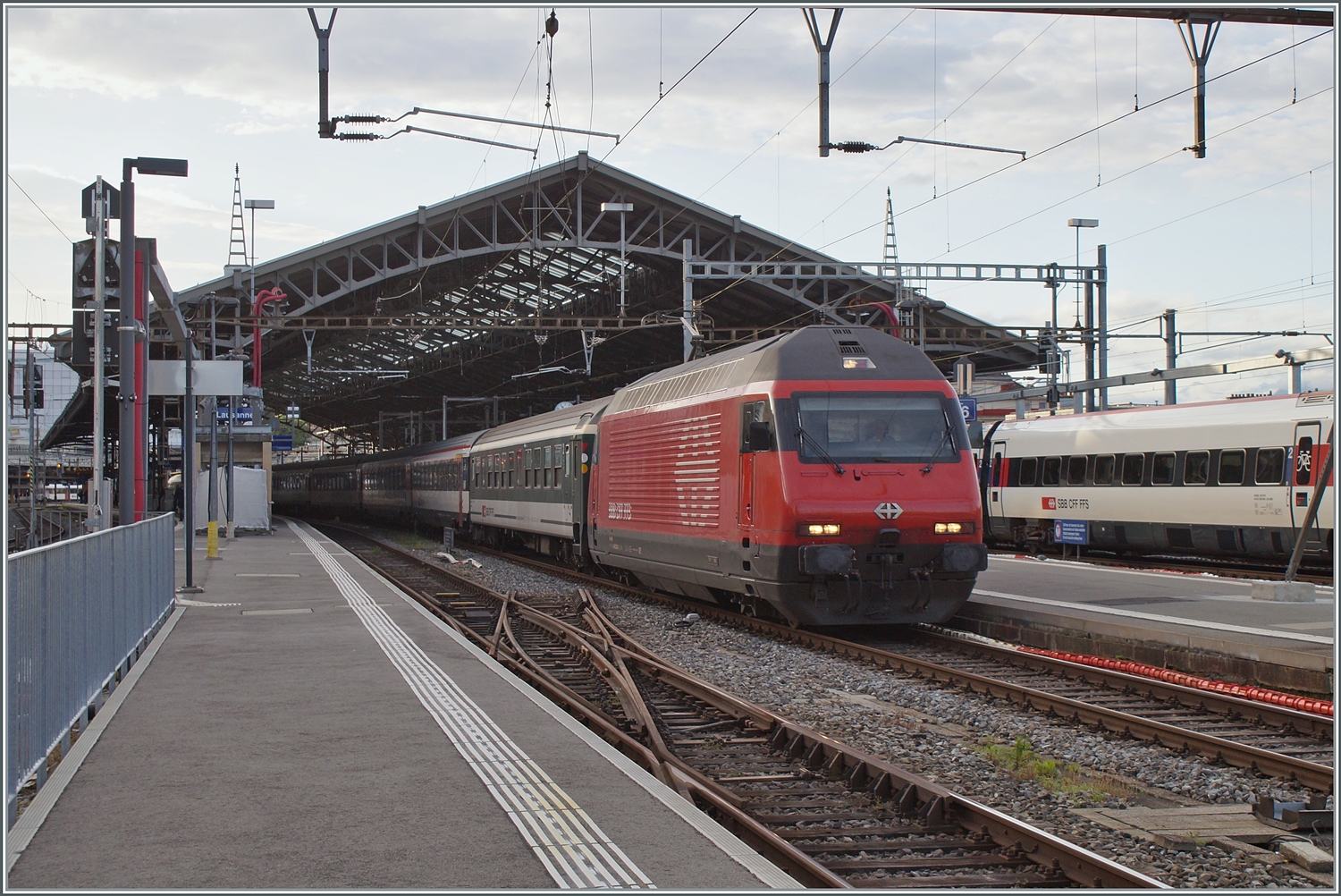 Eine SBB Re 460 verlässt mit ihrem HVZ IR 90 Lausanne in Richtung Genève. Im Vordergrund ist noch eine nicht mehr genutzte DKW zu erkennen, doch das eigentliche Motiv ist der Bpm in Grün/Grau direkt hinter der Lok. Bpm an und für sich sind schon eher selten, in Grün/Grau fast kaum mehr im Planeinsatz zu erleben. Der Wagen hat die UIC Nummer B 50 85 21-73 518-5 CH-SBB. 

17. Mai 2023